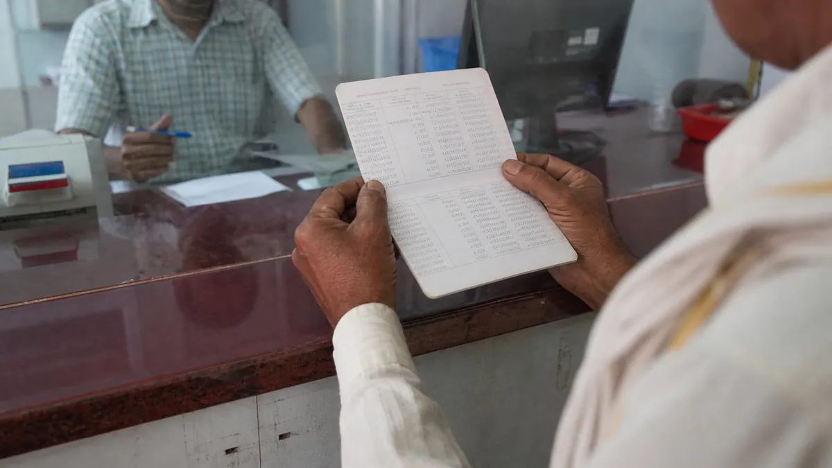 बैंक passbook में entry जांचता किसान